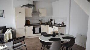 A modern kitchen with white cabinets, a black countertop, and a round dining table with black chairs. - Beautiful vacation apartment near Pietzmoor (Schneverdingen)