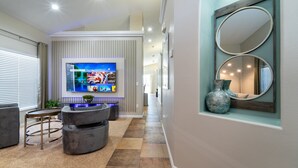 Un salon moderne avec un téléviseur à écran plat, une table basse ronde et un miroir décoratif.
