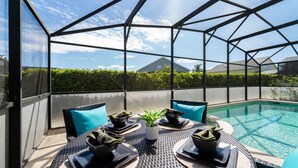 Un espace extérieur aménagé pour les repas, doté d’une structure vitrée, d’une piscine et offrant une vue sur le quartier.