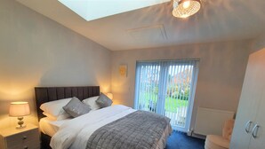 Een slaapkamer met een bed, nachtlampjes, een radiator en uitzicht.