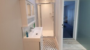 Een badkamer met een douche, een wastafel en een spiegel.