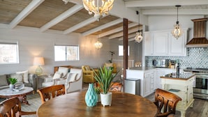A spacious kitchen with wooden cabinets, a dining area with a round table, and a living room with a sofa and chairs. - Lakefront Family Getaway | Dock, Hot Tub, Kings (Lakeport)