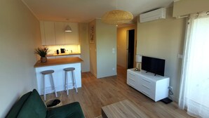 A compact living space with a kitchenette, a TV, a sofa, and a dining area.