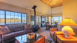 A cozy living room with a fireplace, leather sofa, dining table, and a view of the outdoors. - On Lake Hatcher! Great Views, Quiet Area, Close to Uptown, New Hot Tub! (Pagosa Springs)