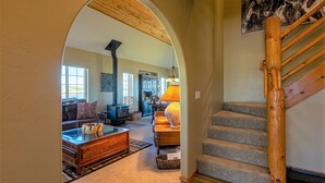 A cozy living room with a fireplace, a staircase, and a dining area. - On Lake Hatcher! Great Views, Quiet Area, Close to Uptown, New Hot Tub! (Pagosa Springs)