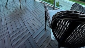 En balkon med fletningsmøbler, udsigt til høje bygninger og palmer.