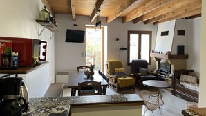 Ein gemütliches Wohnzimmer mit Kamin, Fernseher und Essbereich mit Kaffeemaschine.