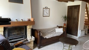 Ein gemütliches Wohnzimmer mit Kamin, einer hölzernen Bank, einer Couch und einem kleinen runden Tisch.