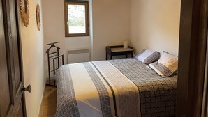 Ein Schlafzimmer mit Bett, Fenster, Heizkörper, Nachttisch und Pendelleuchte.
