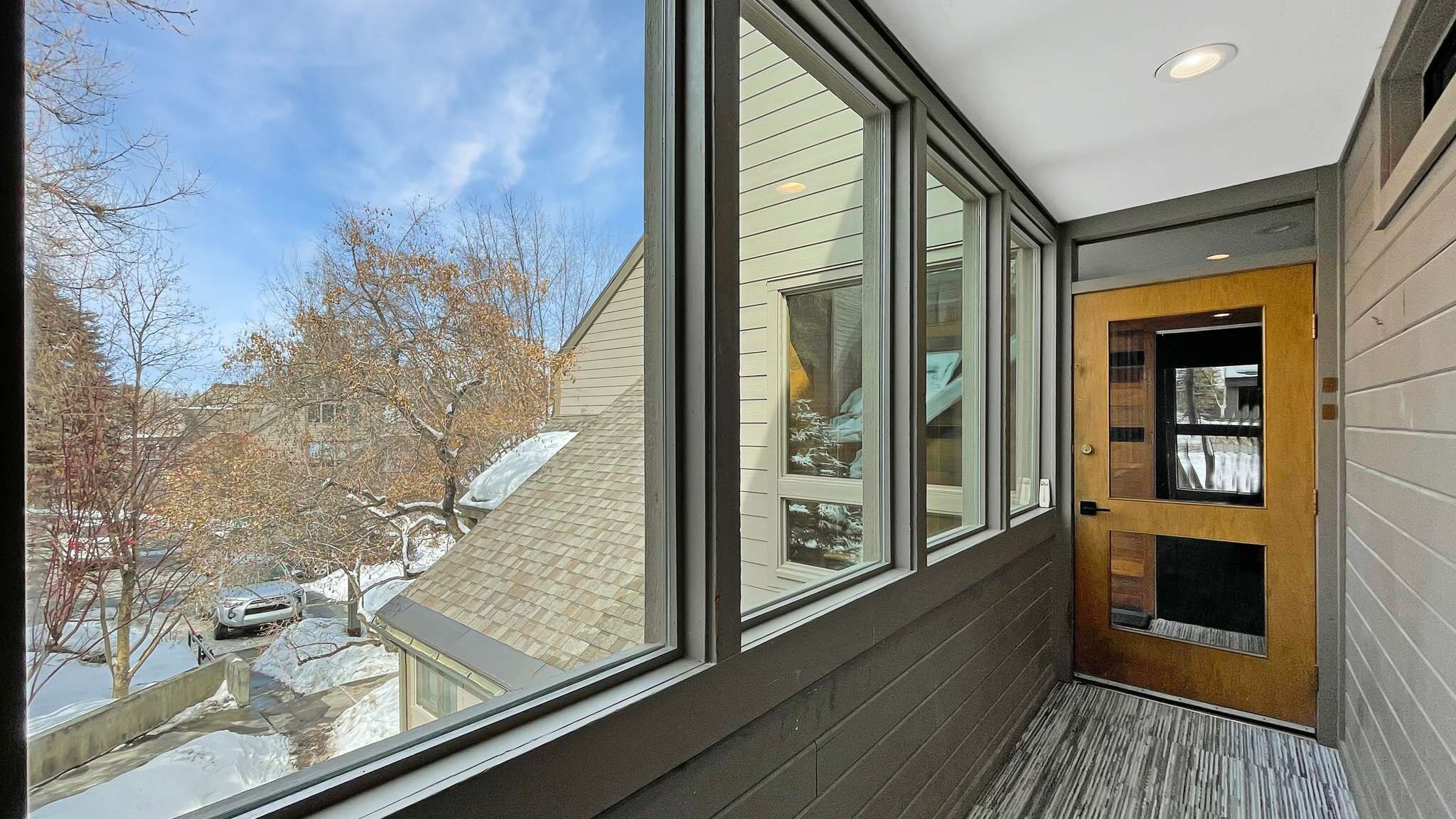 Un interior moderno con ventanas amplias, una puerta de madera y vistas a un paisaje nevado.