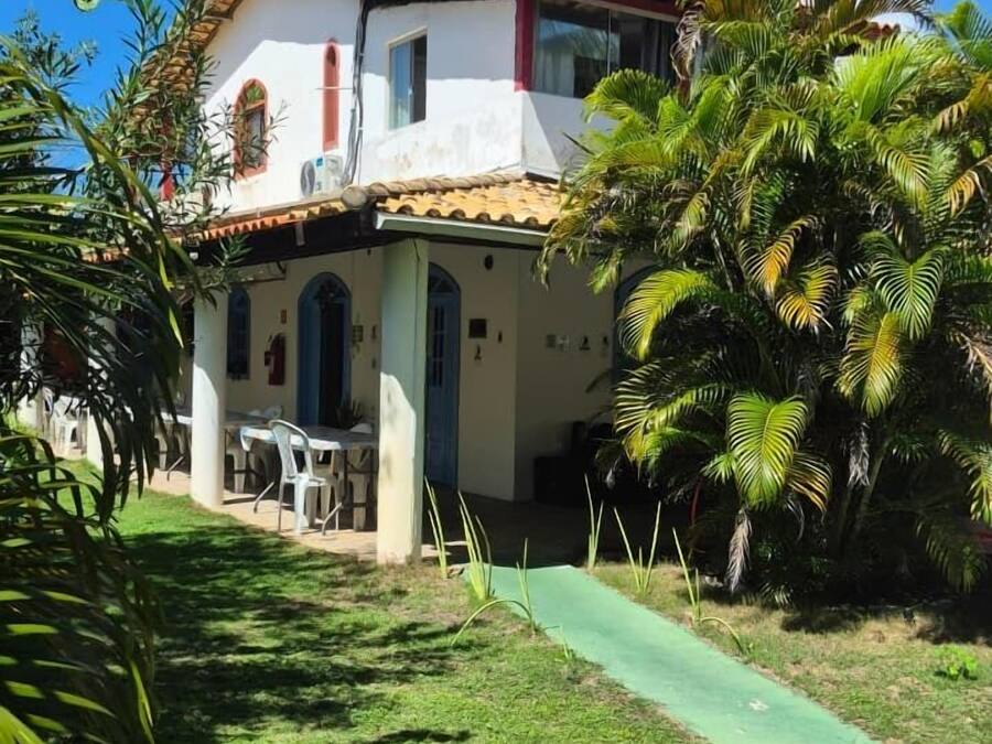 Ein zweistöckiges Haus mit Ziegeldach, einem kleinen Balkon und einem grünen Weg, der zum Eingang führt.