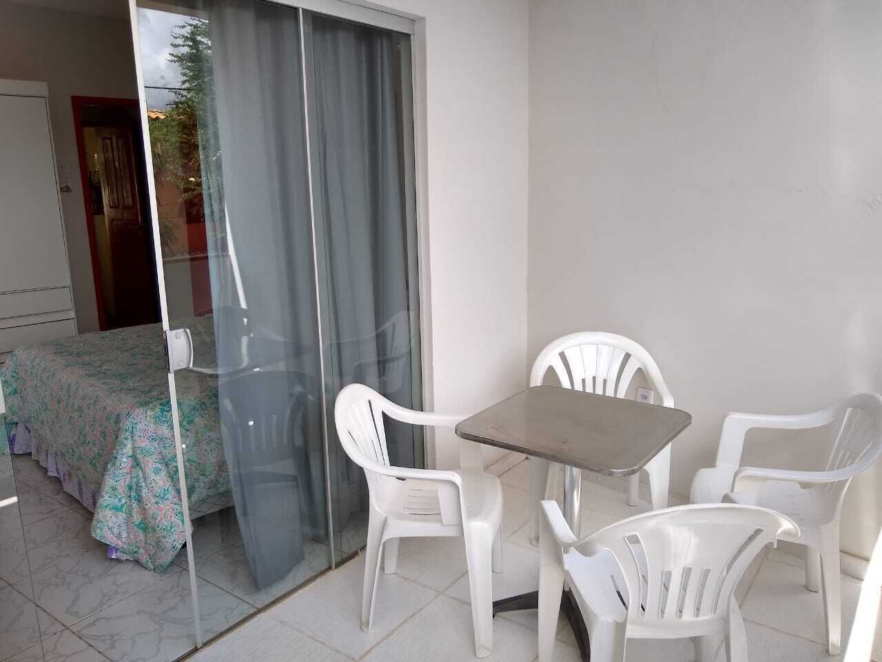 A balcony with a table and chairs, a sliding glass door, and a bed with a floral bedspread.