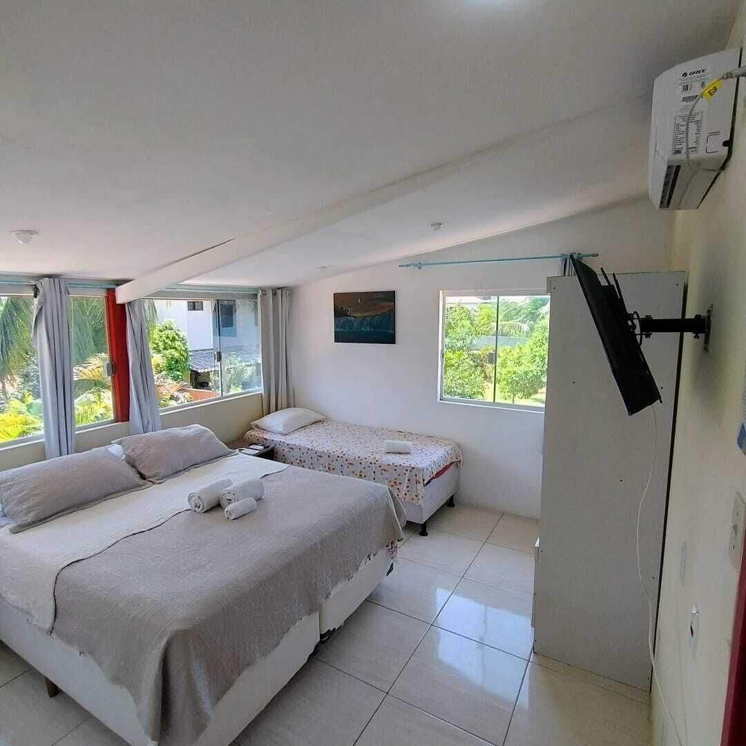 Un dormitorio con dos camas, una ventana y un equipo de aire acondicionado.