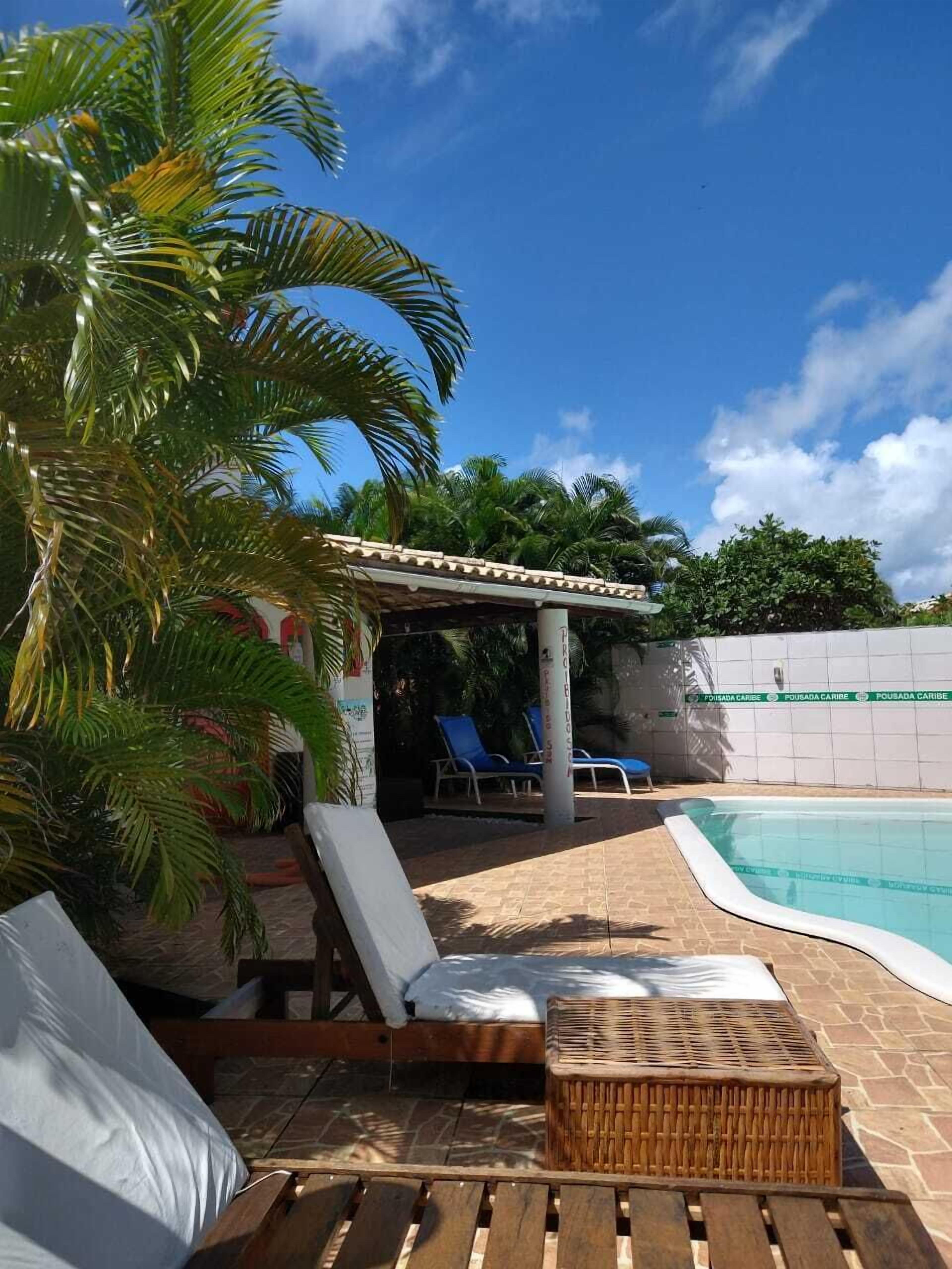 Un espace aménagé au bord de la piscine, avec des chaises longues, une petite table et un coin salon abrité.