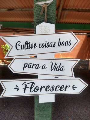 Een bord met de tekst 'Cultive coisas boas para a Vida Florescer' bevestigd aan een groene paal.