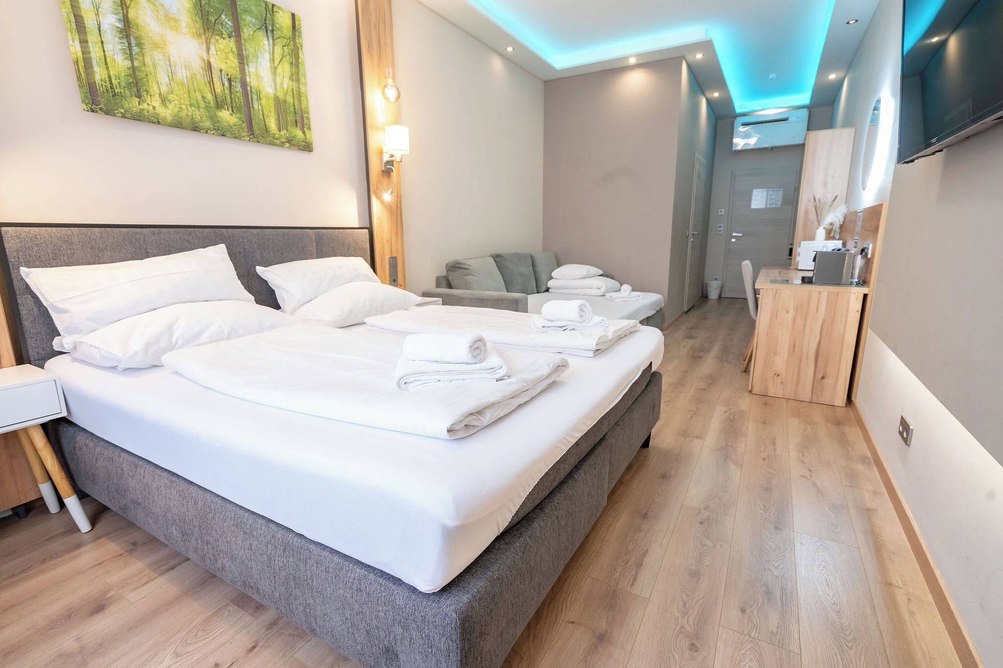 Een hotelkamer met een groot bed, een bureau, een stoel en een schilderij aan de muur.