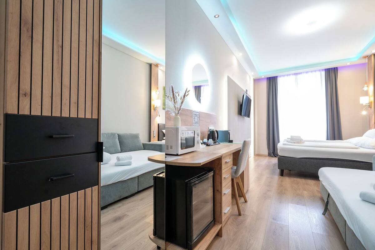 Een moderne hotelkamer met kitchenette, een bank, een bed en een televisie.