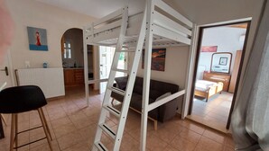 Una habitación con literas, una kitchenette pequeña, una zona de comedor y un baño.