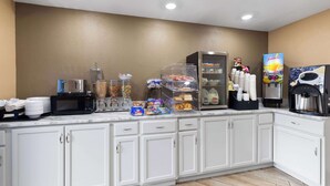 A self-service breakfast area with a microwave, cereal, juice, and coffee machine.