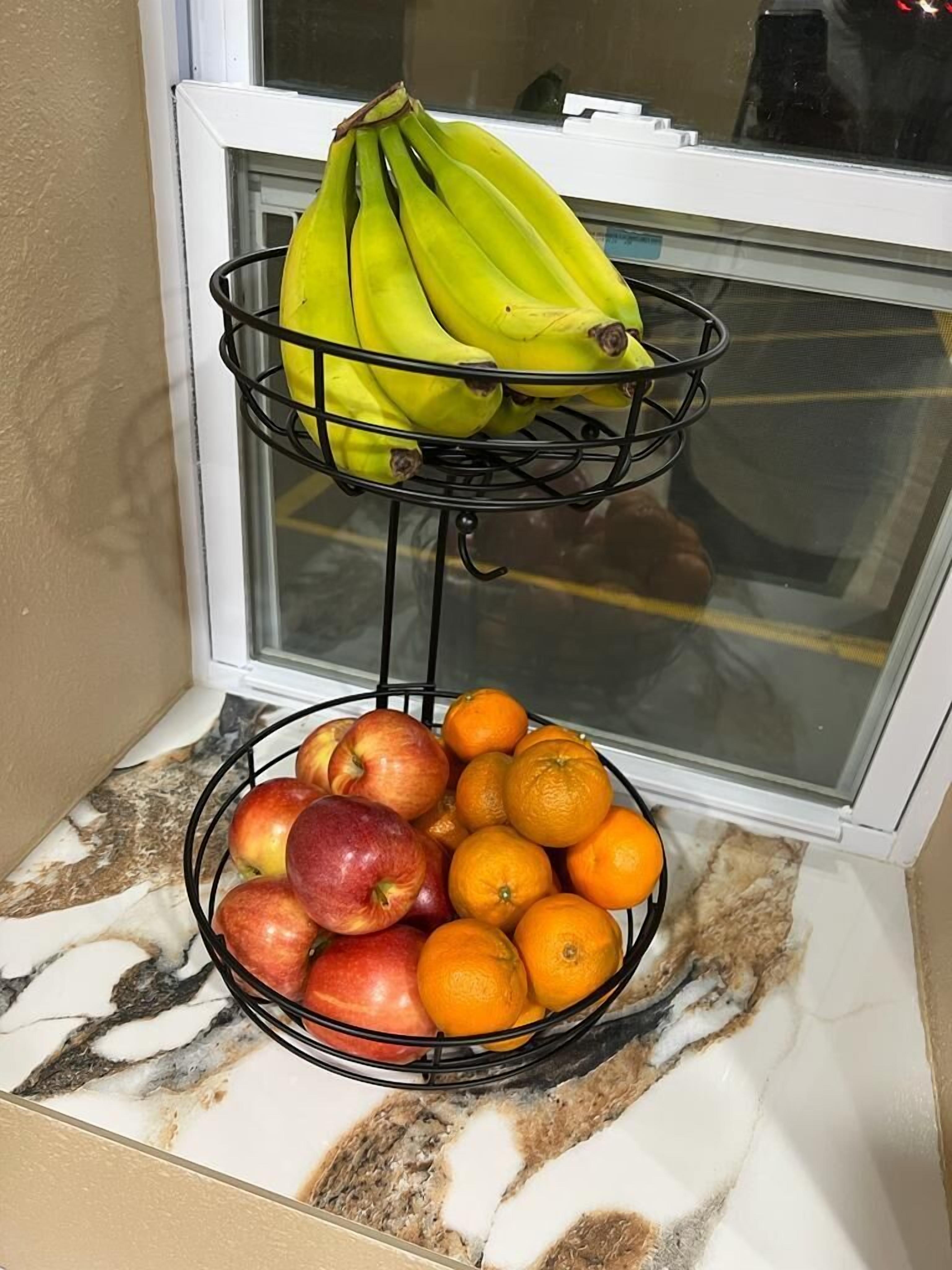 Una cesta de frutas sobre una encimera de cocina con plátanos y manzanas.