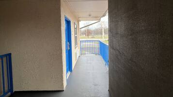 A corridor with an exit sign, blue doors, and a concrete floor.