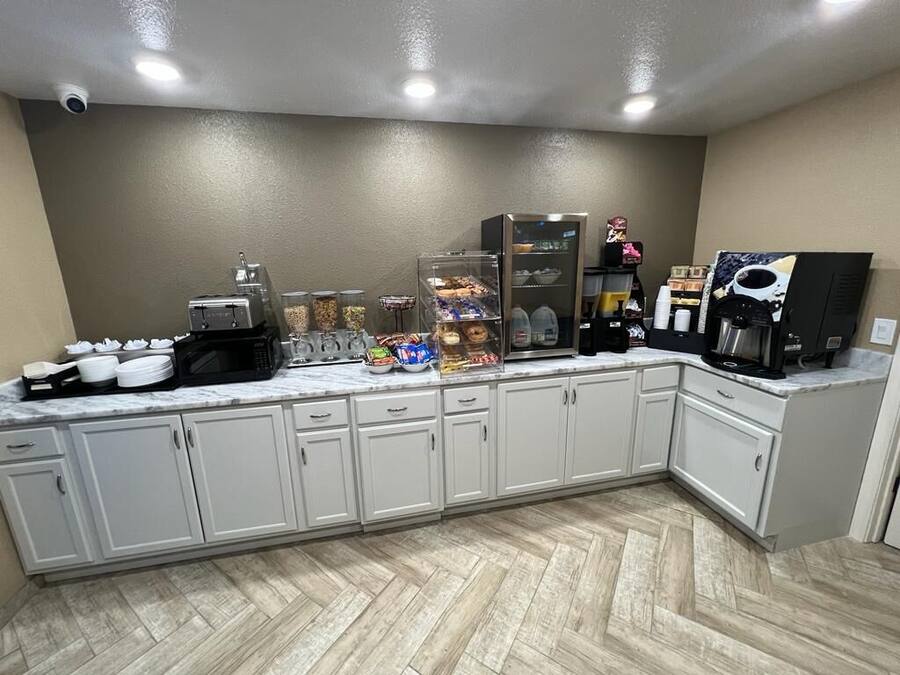 A kitchen with white cabinets, a microwave, a coffee machine, and various food items on the counter.