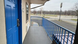 A covered outdoor area with a blue door, a concrete floor, and a blue railing.