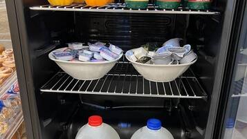 A refrigerated display case with various food items including yogurt, milk, and fruits.