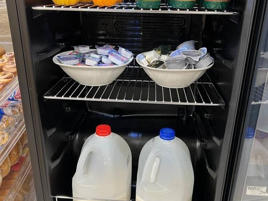 A refrigerated display case with various food items including yogurt, milk, and fruits.