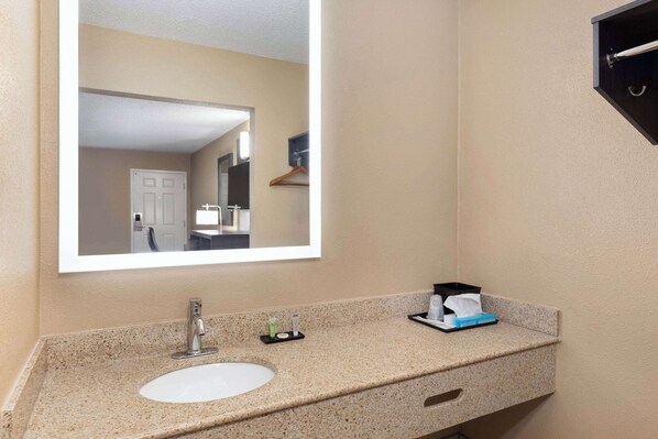 A bathroom with a sink, mirror, and toiletries.