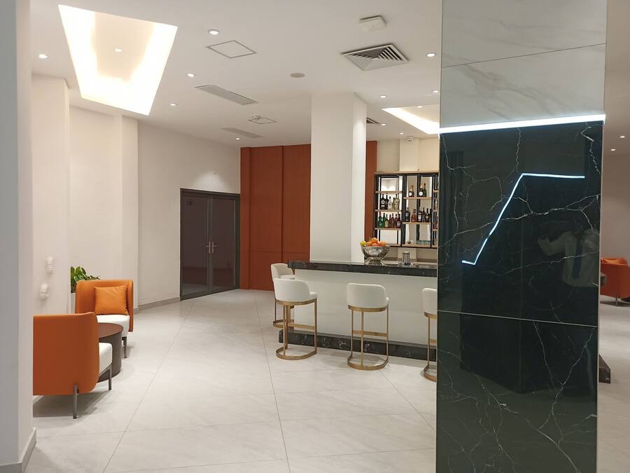 Un moderno vestíbulo de hotel con área de bar, asientos y una pared de acento de mármol.