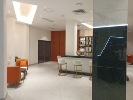 A modern hotel lobby with a bar area, seating, and a marble accent wall.