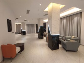 A modern hotel lobby with marble columns, a reception desk, and seating areas.