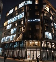 A multi-story hotel with a modern design, featuring a prominent 'AXIL HOTEL' sign.