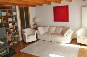 A living room with a white sofa, a white armchair, and a bookshelf.