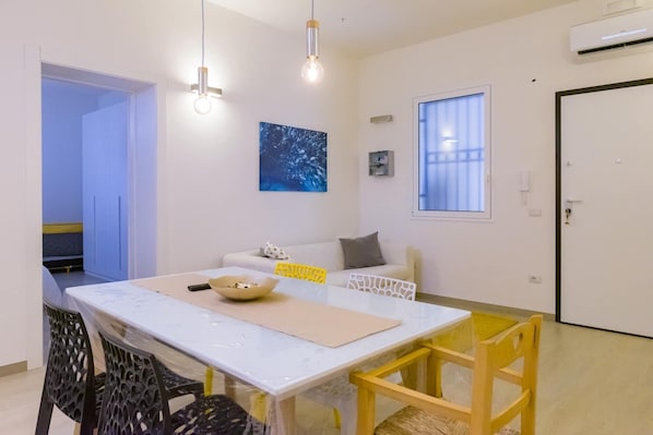 A dining area with a white table, yellow chairs, and a painting on the wall.
