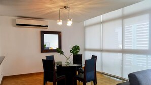 A dining area with a round table, chairs, and a potted plant.