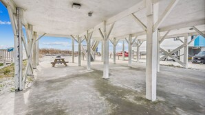 A covered outdoor area with concrete flooring and white structural beams. - Pet Friendly Ocean Front Home - Shore Delight (North Myrtle Beach)