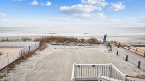 A concrete pathway leading to a beach with a wooden fence and a signpost. - Pet Friendly Ocean Front Home - Shore Delight (North Myrtle Beach)