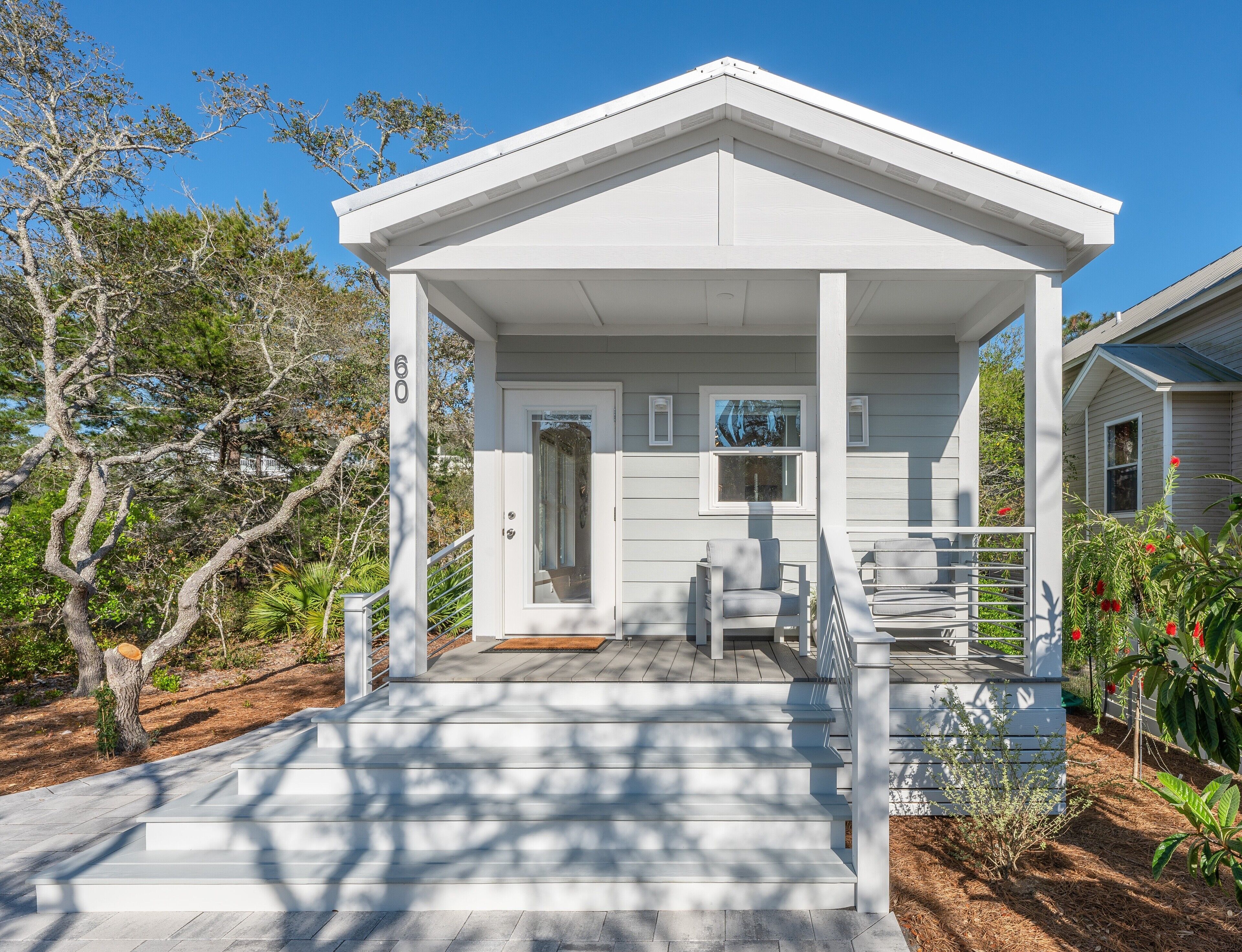 A white building with a covered porch, a door, and a small window.
