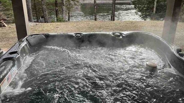 A hot tub with a view of a lake and trees.
