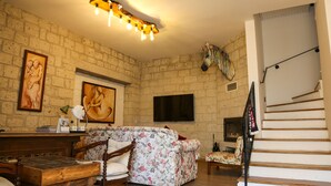 A living room with a wooden table, floral sofa, and a staircase. - Rikas Alacati (Cesme)