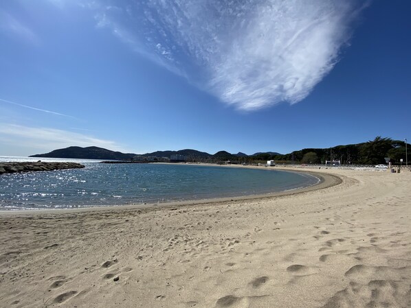 A sandy beach with clear blue water and a curved shoreline.
