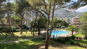 A pool area surrounded by trees and a view of a hillside residential area.