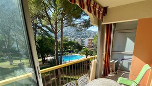 A balcony with a table and chairs, a pool, and a view of a residential area.