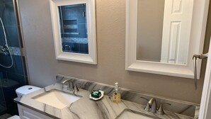 Une salle de bain avec deux lavabos, des toilettes, une douche et un miroir.