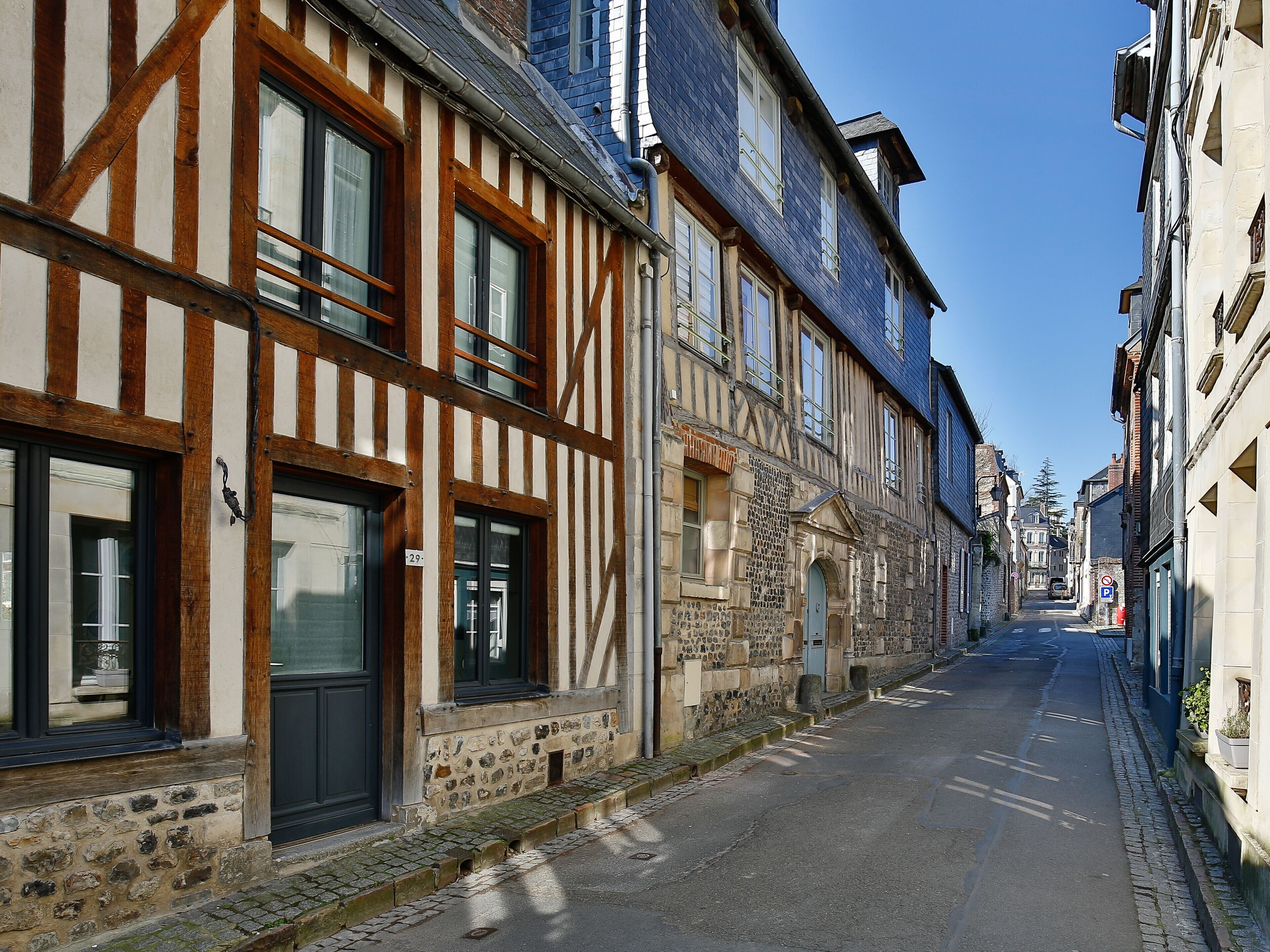 A narrow street lined with traditional half-timbered buildings, stone walls, and a cobblestone path.