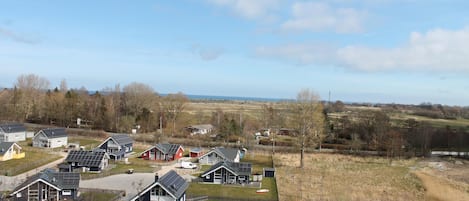 A residential area with houses featuring solar panels, a clear sky, and a distant view of the sea.