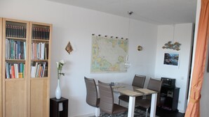 Et spiseområde med et bord, stole, et kort på væggen og en reol.