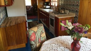 Een gezellige keuken met houten kastjes, een fornuis en een eethoek met een tafel en stoelen.
